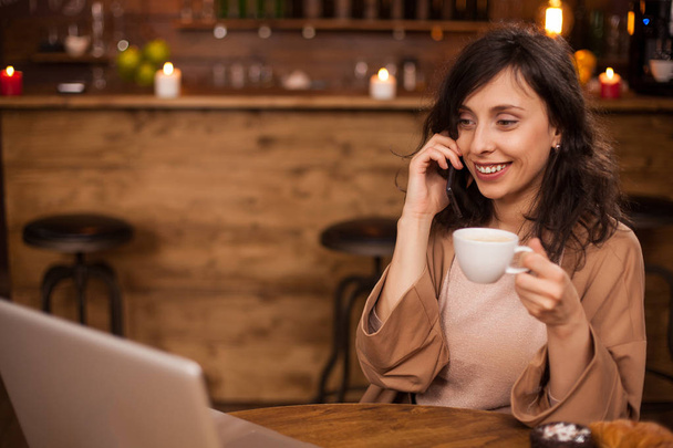 Alegre mujer de negocios sonriente y mirando su computadora portátil en una cafetería
 - Foto, imagen