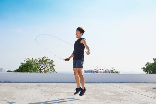 Fitness, Sport, Menschen, Bewegungs- und Lifestylekonzept - Mann springt mit Springseil im Freien - Foto, Bild