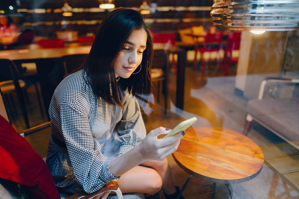 брюнетка девушка с помощью мобильного телефона, чтобы связаться с другом
 - Фото, изображение