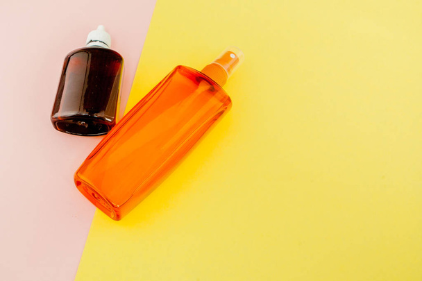 Αντηλιακό μπουκάλι σε φωτεινό τετράγωνο κίτρινο και ροζ φόντο. Teh - Φωτογραφία, εικόνα