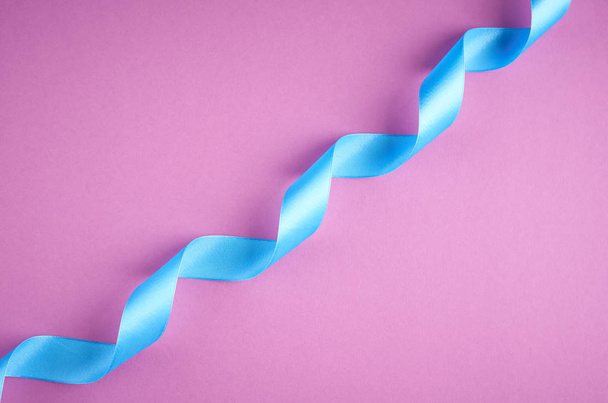 Blue ribbon on purple background composition, flat lay - Photo, image