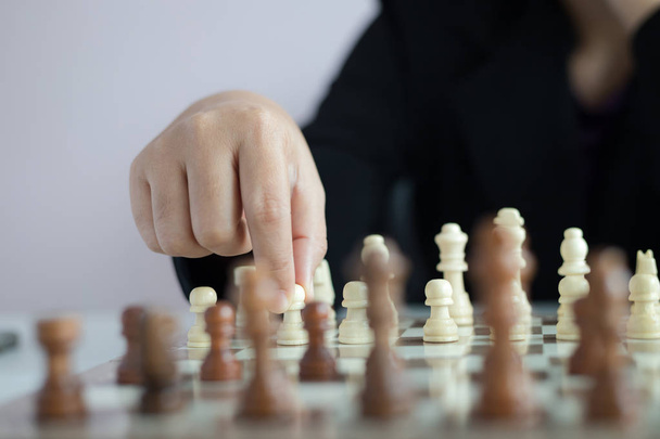 Закройте руку бизнес-леди, играющей на шахматной доске
  - Фото, изображение