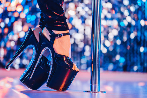 Legs in high sexy shoes near pylone. Striptease dancer moving on stage in strip night club. Pole dancing background. - Zdjęcie, obraz