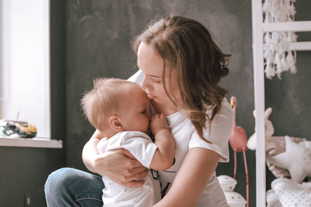 feliz joven mamá niño bebé luz beige fondo abrazando felizmente
 - Foto, Imagen