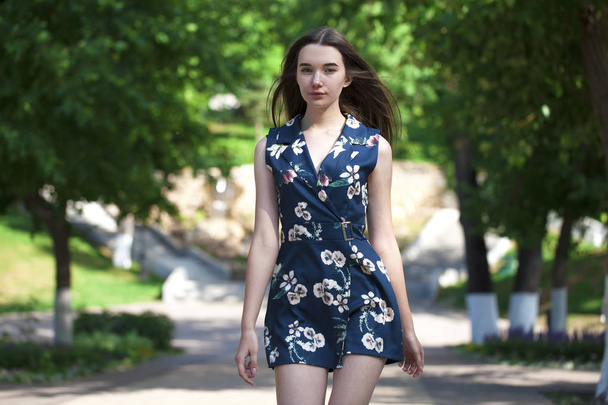 Young beautiful woman in a blue short dress walking on the road - Fotografie, Obrázek