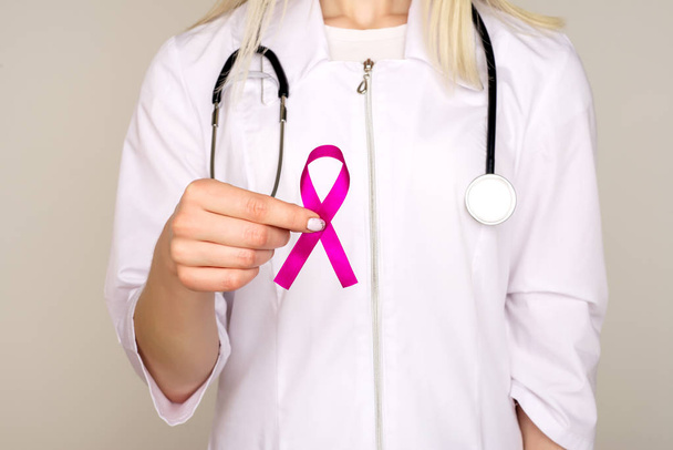 Female Doctor Holds Pink Ribbon, International Breast Cancer Day - Фото, изображение