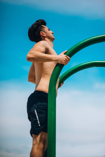 Fit masculino fazendo mergulhos tríceps em barras de metal no parque da cidade
 - Foto, Imagem