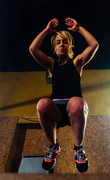 ταιριάζει γυναίκα εκτελεί άλματα κουτί στο γυμναστήριο - Φωτογραφία, εικόνα