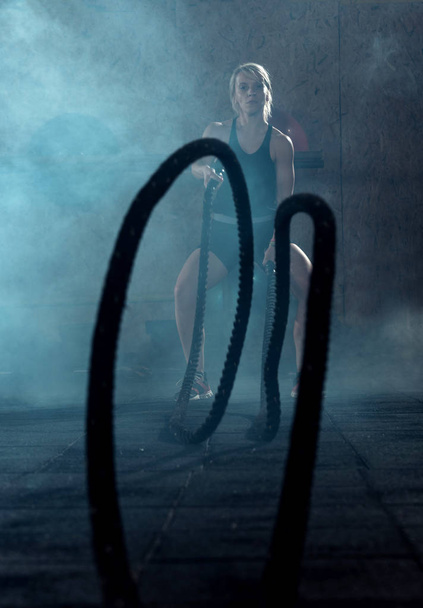 Mujer haciendo ejercicio con cuerdas de batalla en el centro crossfit
  - Foto, Imagen