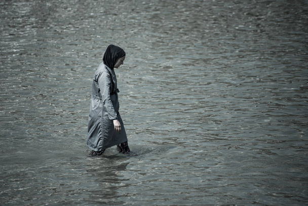 Muslim woman taking a swim in the sea full covered with clothes - Foto, imagen