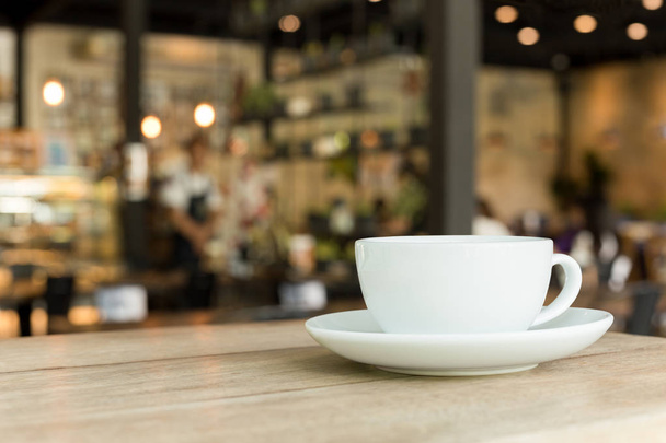 Tazza di caffè su tavolo in legno in caffè con sfondo sfocato
. - Foto, immagini