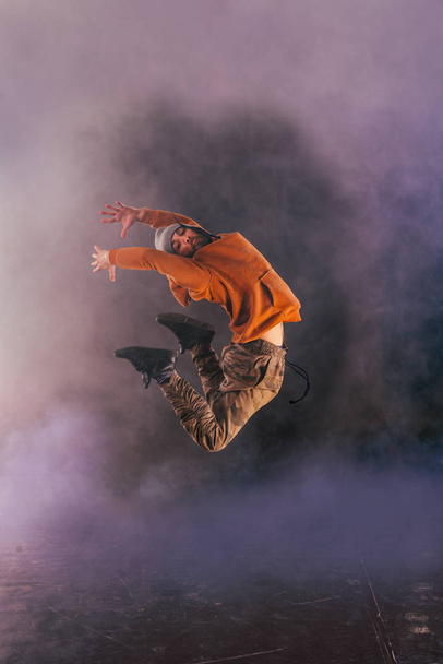 Мужчина-брейкдансер прыгает высоко в воздух, выполняя кооператив
 - Фото, изображение