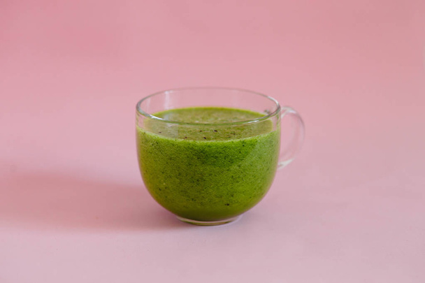 Smoothie verde saludable con kiwi y manzana en una taza de vidrio sobre fondo rosa
 - Foto, imagen