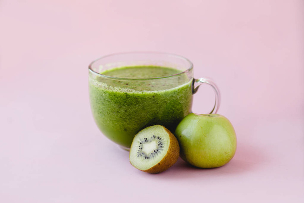 Smoothie verde saudável com kiwi e maçã em uma xícara de vidro no fundo rosa
 - Foto, Imagem