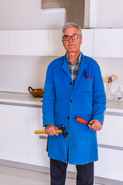 Obrero parado en cocina blanca con sus herramientas y trabajando con su martillo
 - Foto, imagen
