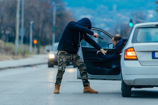 Ο κλέφτης αυτοκινήτων είναι τραβώντας τον ιδιοκτήτη του αυτοκινήτου από το αυτοκίνητό του και να προσπαθεί - Φωτογραφία, εικόνα