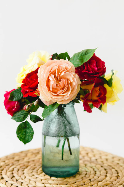 Coloful rosas em vaso em um guardanapo de vime no fundo branco
 - Foto, Imagem