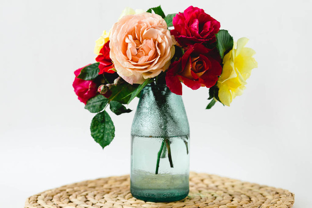 Coloy Roses in vaas op een rieten servet op witte achtergrond - Foto, afbeelding