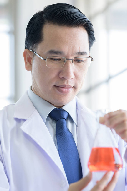 Ázsiai laboratóriumi tudós férfi dolgozik a laborban teszt piros cső - Fotó, kép