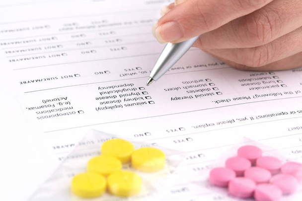 Pílulas coloridas e escrita de mão no formulário de questionário médico
 - Foto, Imagem