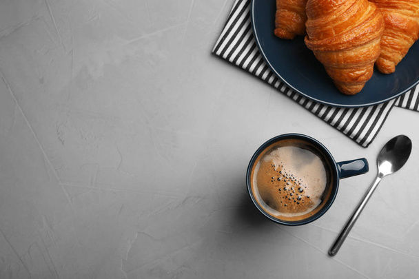 灰色のテーブルの上にコーヒーとクロワッサンとフラットレイコンポジション、テキスト用のスペース - 写真・画像