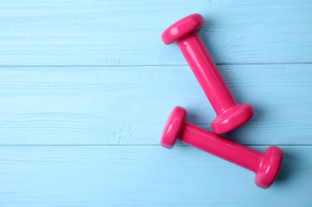 Bright dumbbells and space for text on wooden background, flat lay. Home fitness - Foto, immagini