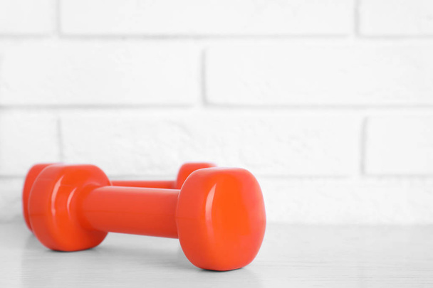 Stylish dumbbells on table against brick wall, space for text. Home fitness - Foto, Imagen