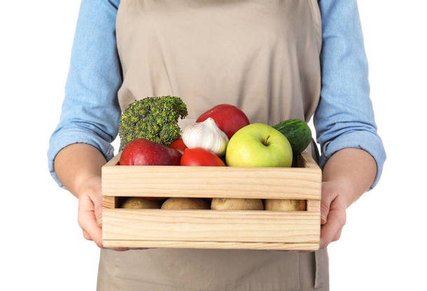 Woman holding wooden crate filled with fresh vegetables and fruits against white background, closeup - Photo, image
