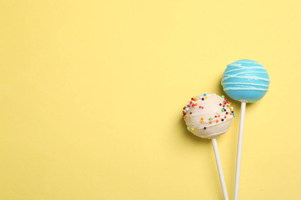 Bright delicious cake pops on color background, flat lay. Space for text - Photo, image
