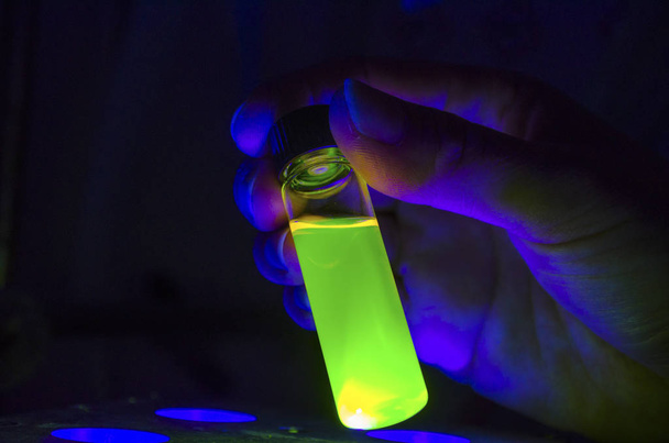 Χέρι ερευνητή που κρατά πράσινη φωτοχημική αντίδραση στο γυαλί VI - Φωτογραφία, εικόνα