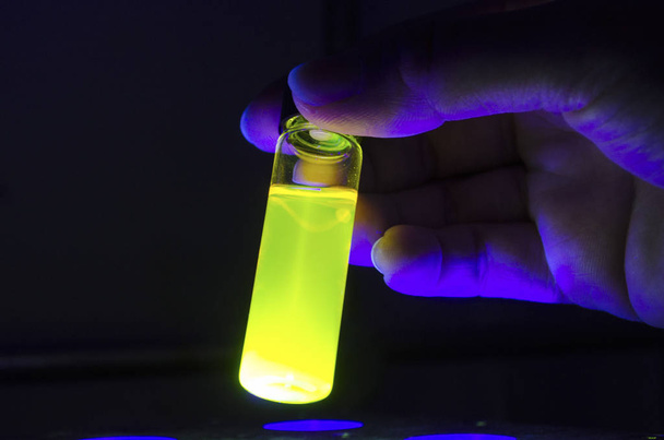 Ερευνητής χεριού με κίτρινο κοντινό επάνω φωτοχημική αντίδραση  - Φωτογραφία, εικόνα