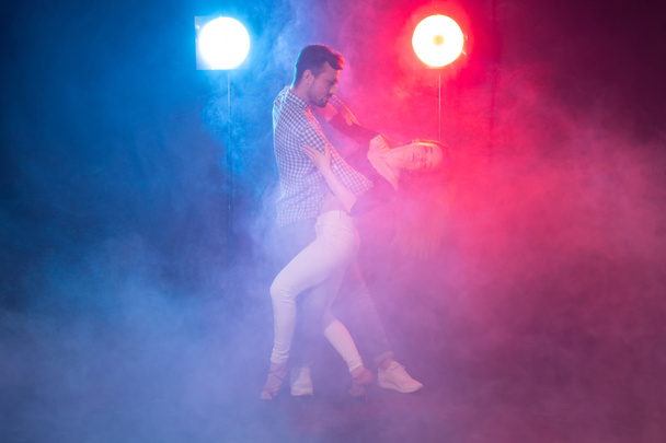 Sosyal dans, Bachata, Kizomba, Zouk ve tango kavramı-adam sarılırken kadın ışıklar üzerinde dans ederken - Fotoğraf, Görsel
