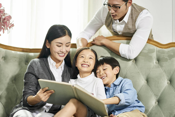 asian mother and father and two children reading book together - Photo, Image