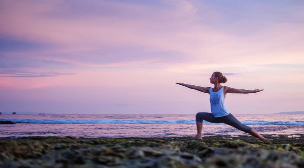 Caucasian woman practicing yoga at seashore - Foto, afbeelding