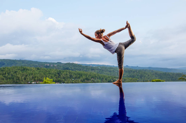 Caucasian woman practicing yoga by the pool - Zdjęcie, obraz