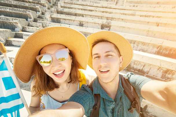 Europejski mężczyzna i Asian Girl w miłości kilka turystów wziąć selfie w starożytnym greckim Akropolu z flagą. Podróże i przygoda w Grecji - Zdjęcie, obraz