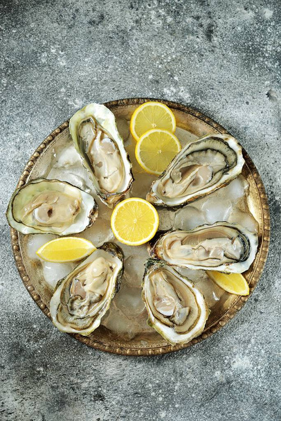 Ouvrir les huîtres fraîches avec des tranches de citron sur un plat avec des glaçons. Vue du dessus
.  - Photo, image