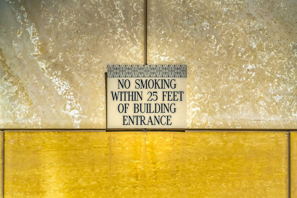 Cartel de no fumar contra la pared blanca y dorada de un edificio
 - Foto, imagen