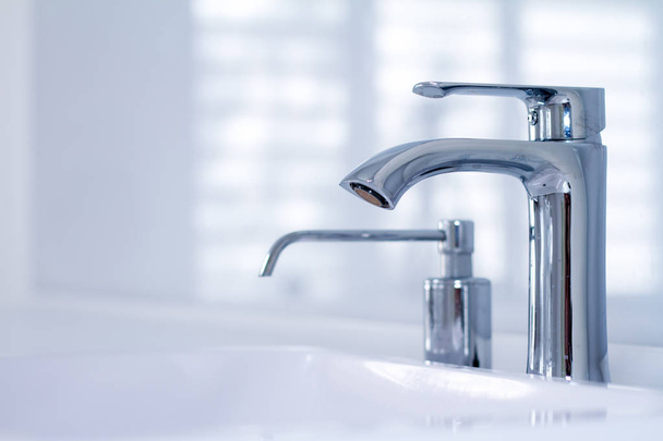 Nowoczesny zlew wody z kranu w minimalistycznym stylu i wbudowany dozownik mydła w drogich łazienka Loft, miękkie ostrości - Zdjęcie, obraz