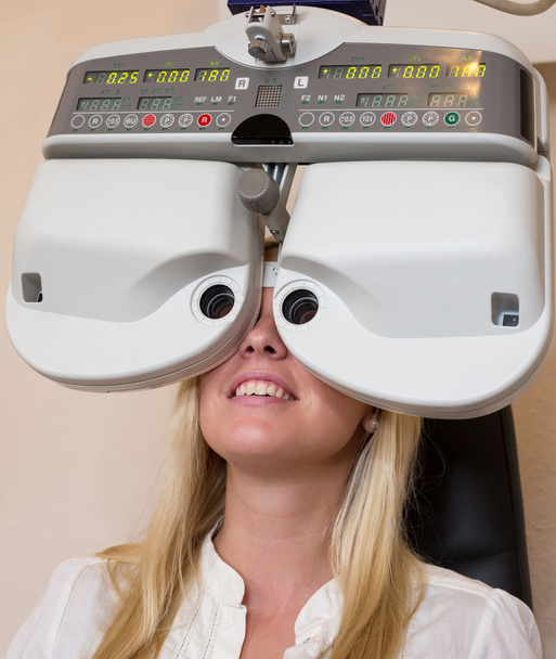 Customer of a optometrist or optician looking through phoropter - Foto, afbeelding