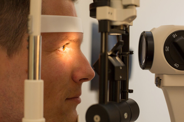 Patient at slit lamp of optician or optometrist - Photo, image