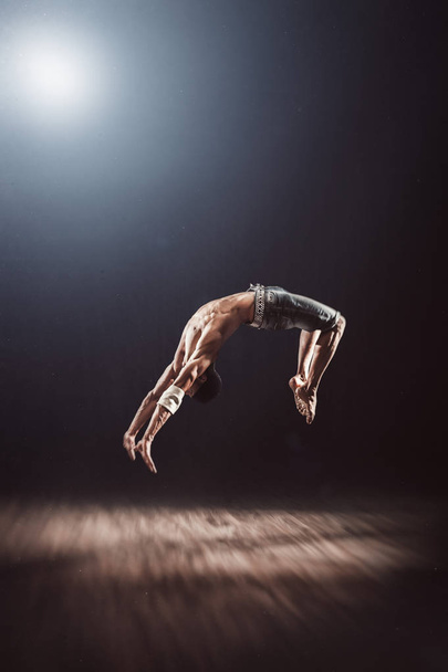 Young man doing acrobatics. Backflip executed by professional and world famous pole athlete. Strong and muscular fitness male model.  - Photo, Image