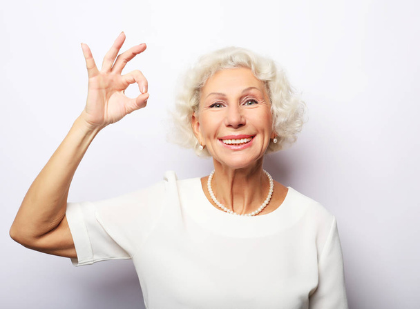happy charming cheerful excited with beaming toothy smile mature lady grandmother granny grandma, she is showing okay sign, isolated on white background - Foto, imagen