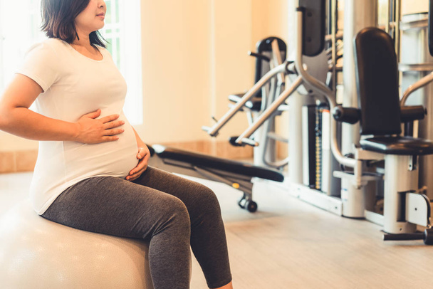 Actieve zwangere vrouw oefening in fitnesscentrum. - Foto, afbeelding