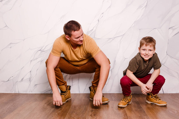 a modern young man and an eight-year-old cheerful boy in orange shoes. father's day - Фото, изображение