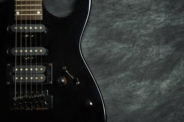 Black electric guitar on black cement floor. - Fotó, kép
