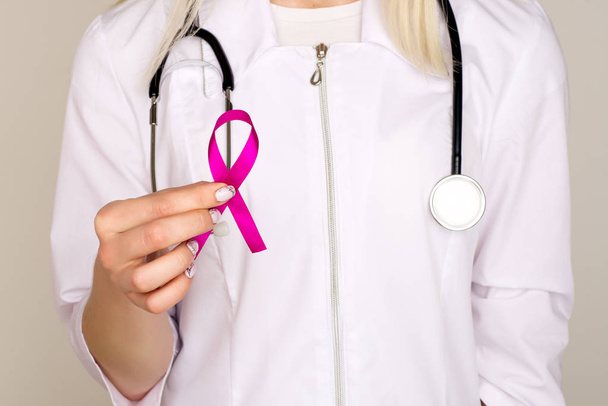 Vrouwelijke arts houdt Pink Ribbon, internationale borstkanker dag - Foto, afbeelding