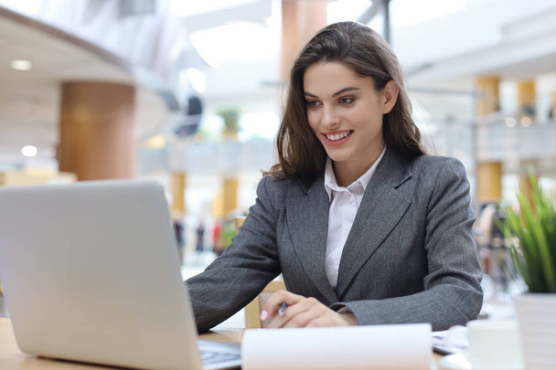 Portrait of a young brunette business woman using laptop at office. - Foto, afbeelding
