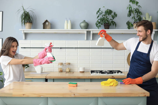 Young happy couple is having fun while doing cleaning at home. - Фото, изображение