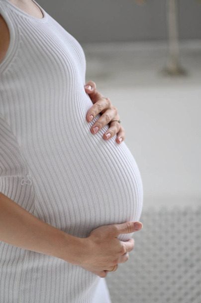 Kobieta w ciąży w białym swetrze trzymając jej brzuch. bliska szczęśliwej ciąży - Zdjęcie, obraz